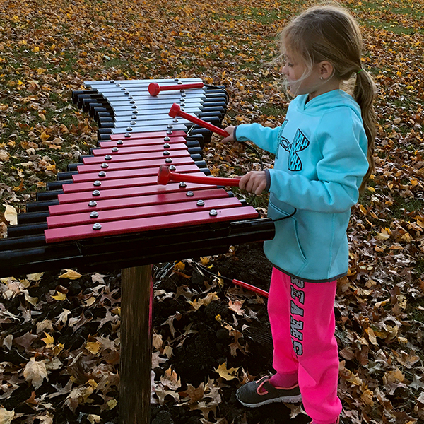 Little girl playing a large outdoor xylophone in Anderson Park City of Essex