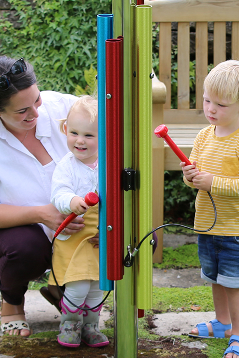 Mother and two children playing a post of musical instruments in a musical playground