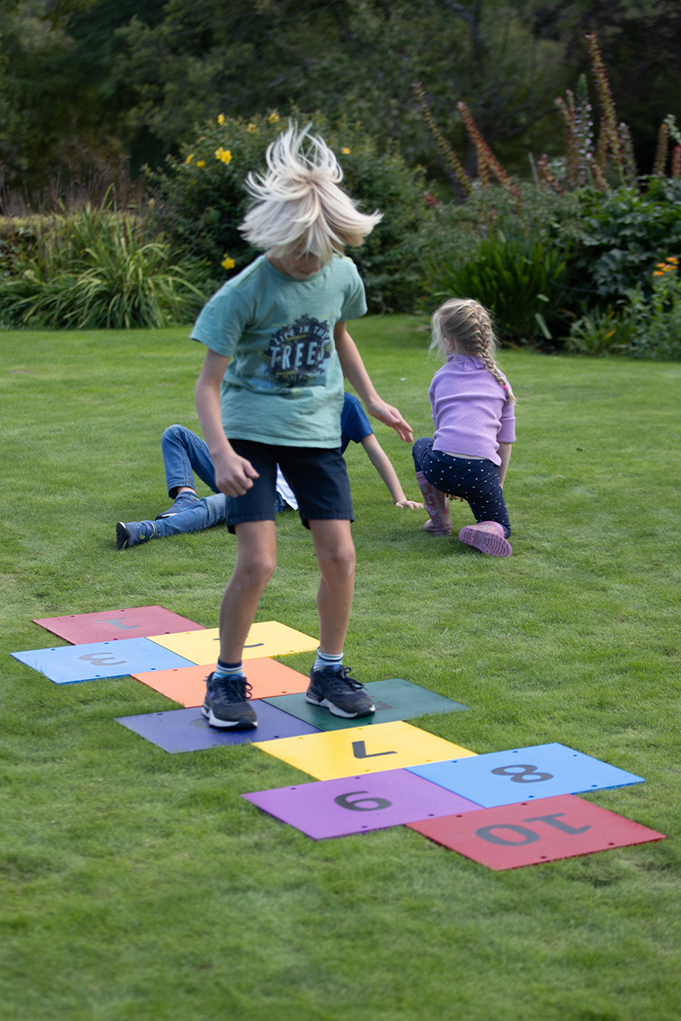 a boy jumping across a colorful outdoor musical hopscotch installed into grass