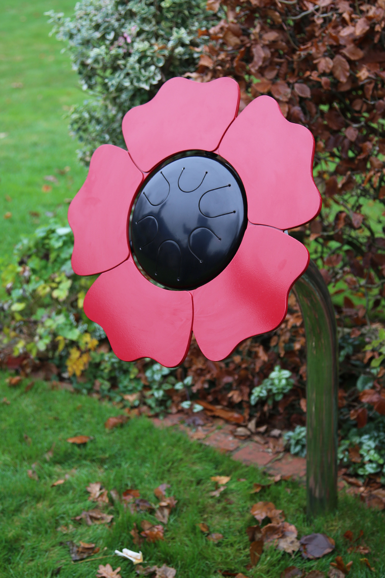 a black tongue drum with red petal surround to make an poppy shaped outdoor musical drum