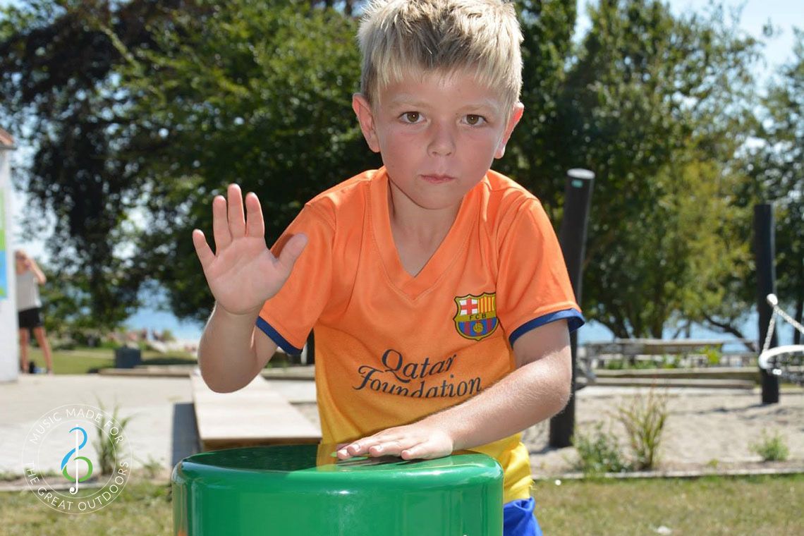 boy playing colourful outdoor drum in playground