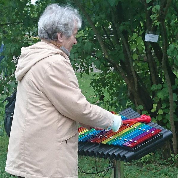 Older lady playing colourful xylophone in a park