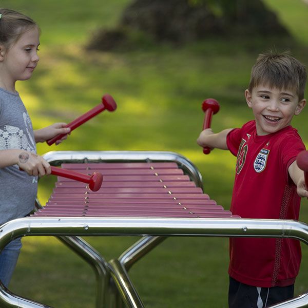 boy and girl playing a large outdoor xylophone in a park