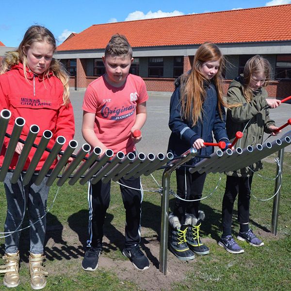 school friends playing a large metallophone in the playground
