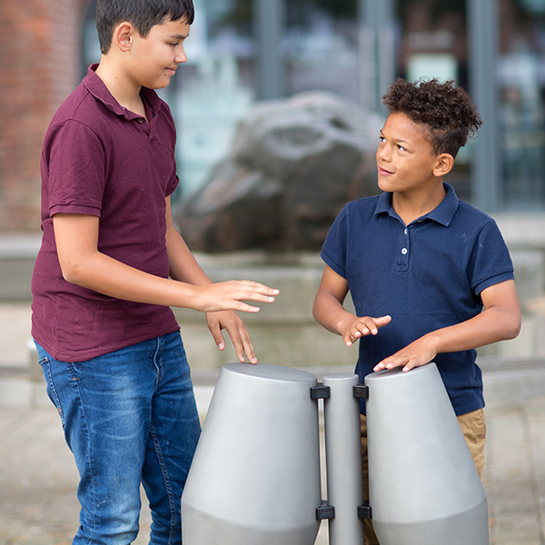 two young brothers are playing a pair of tumbadora steel drums with their hands in the street