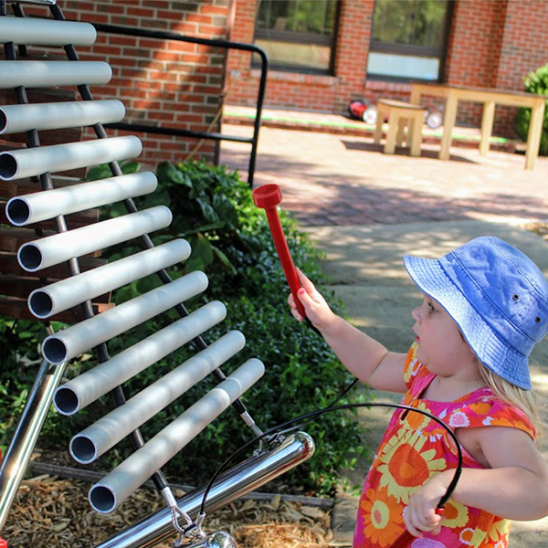a young girl with playing an outdoor musical instrument at the children's healing center