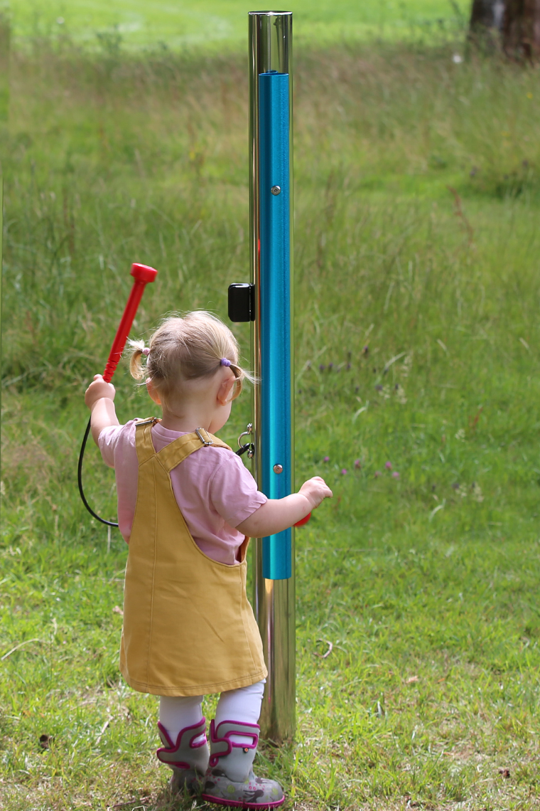 young girl playing on a blue outdoor musical chime