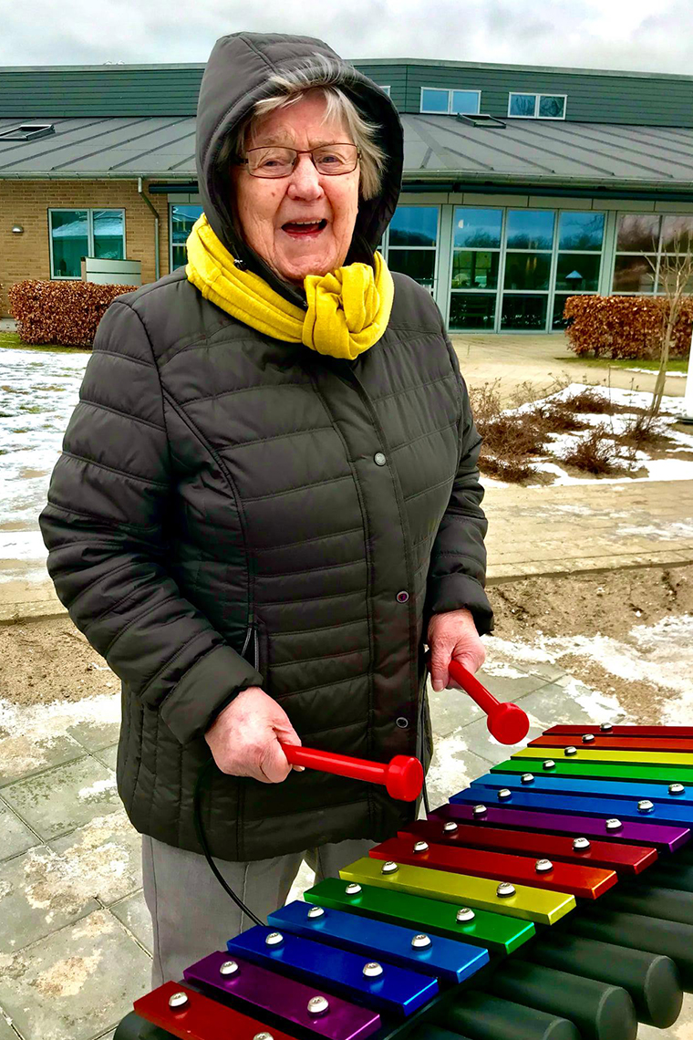 Senior Playing an outdoor musical xylophone called a Cavatina with a Music Book in Winter