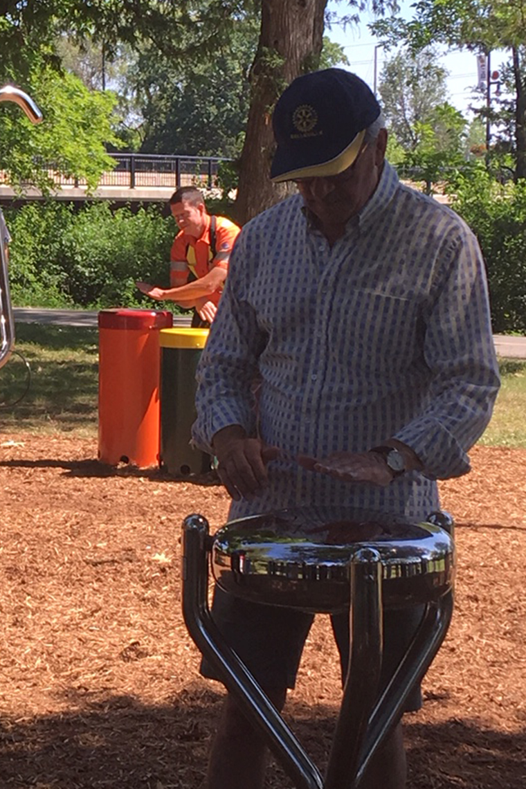 senior playing an outdoor stainless steel tongue drum in a Rotary Music Park