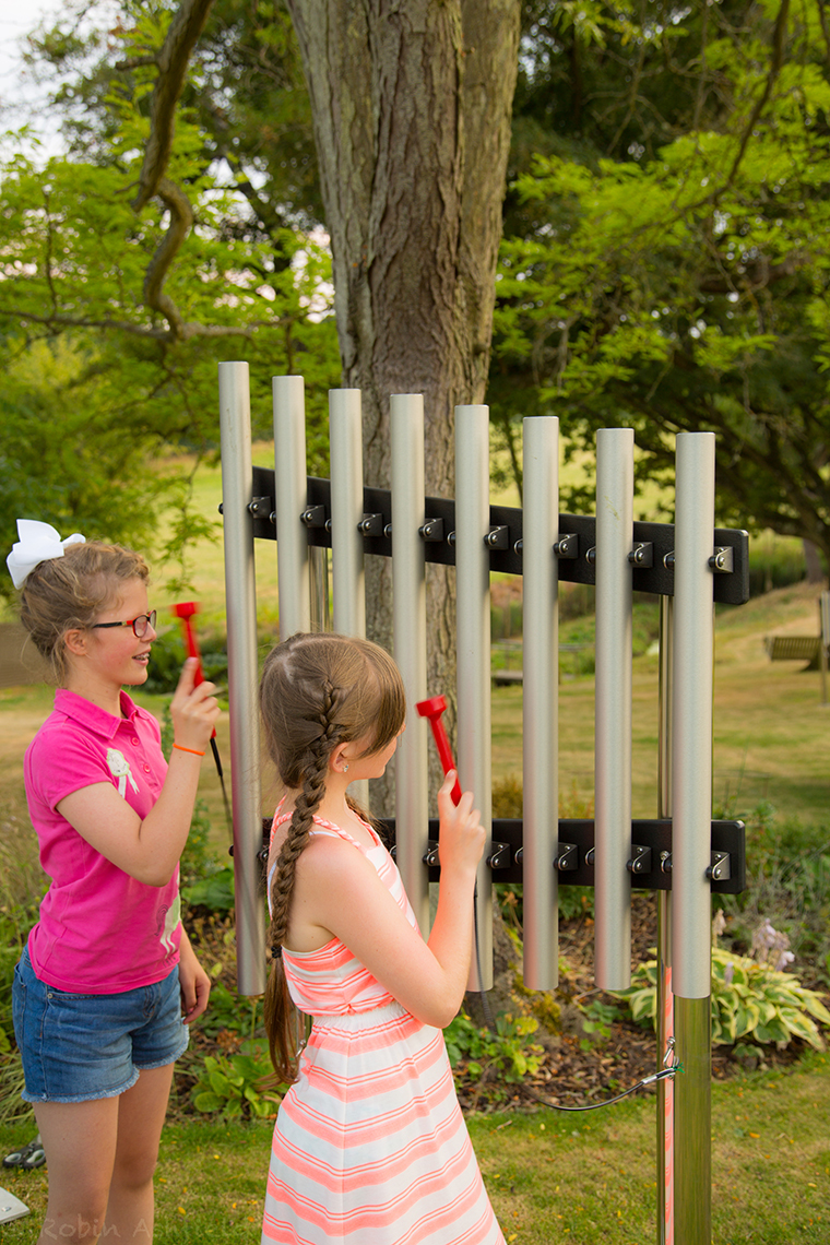 two girls playing on a musical chime set in a garden