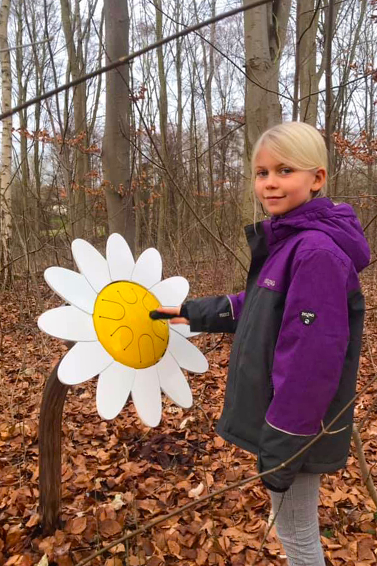 a young blonde girl playing an outdoor drum that looks like a large daisy