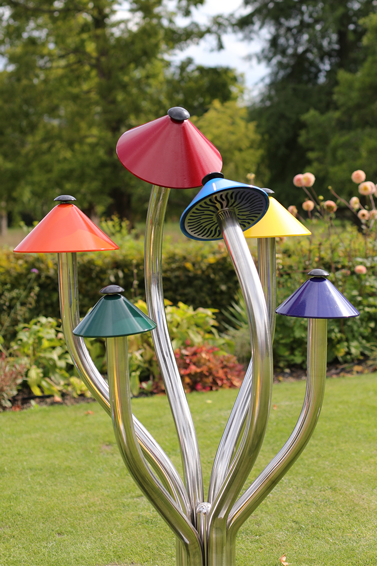 A large outdoor musical instrument shaped like a cluster of liberty cap mushrooms in bright colors
