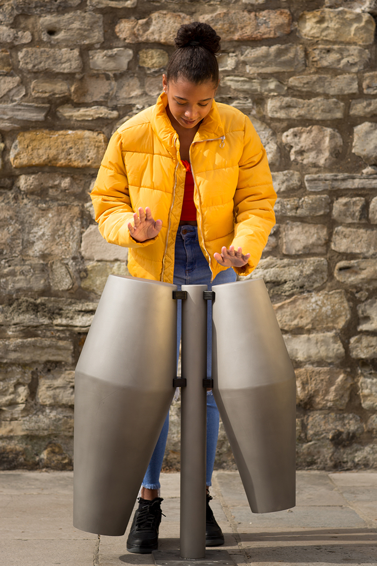 young black girl playing a pair of steel tumbadora drums in the street