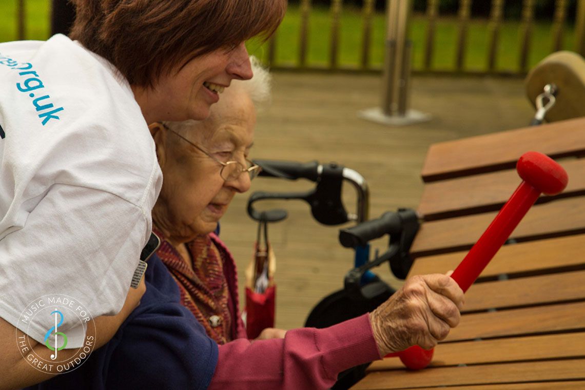 Older Lady and Dementia Carer Playing Outdoor Akadinda Xylophone