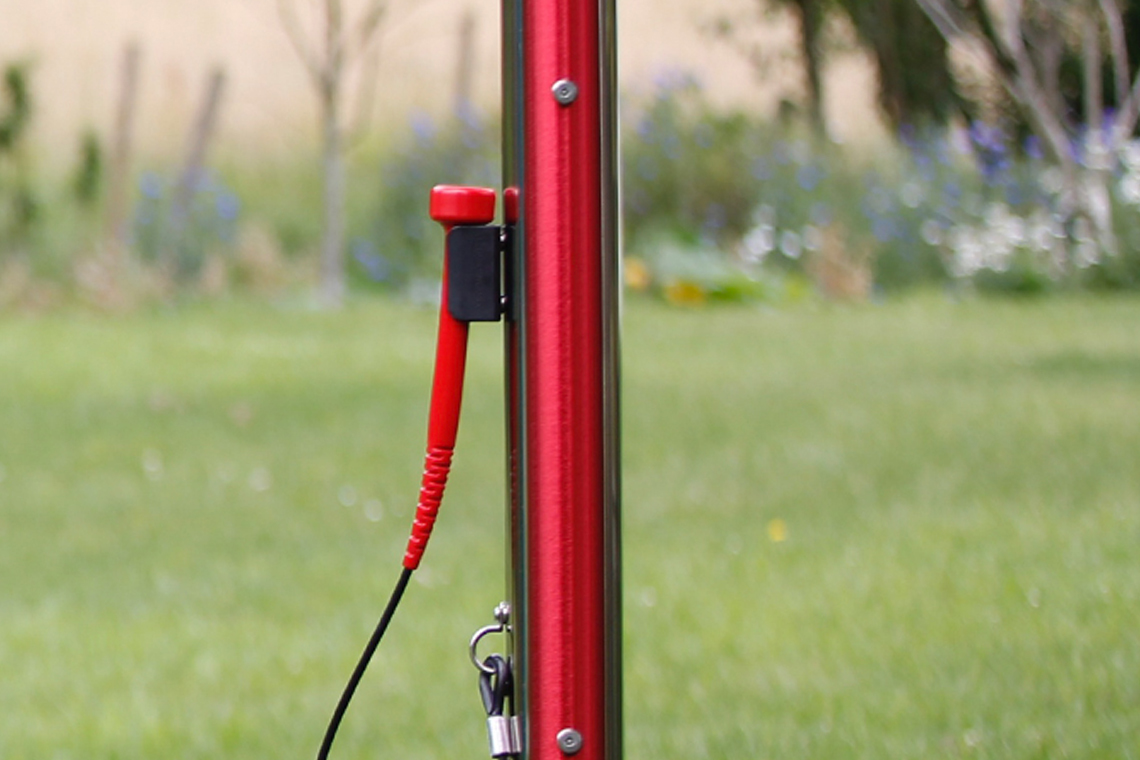 a red outdoor musical chime with mallet in a musical garden