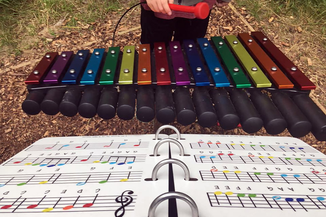 outdoor xylophone with rainbow coloured notes with accompanying music book with the notes colour match the xylophone