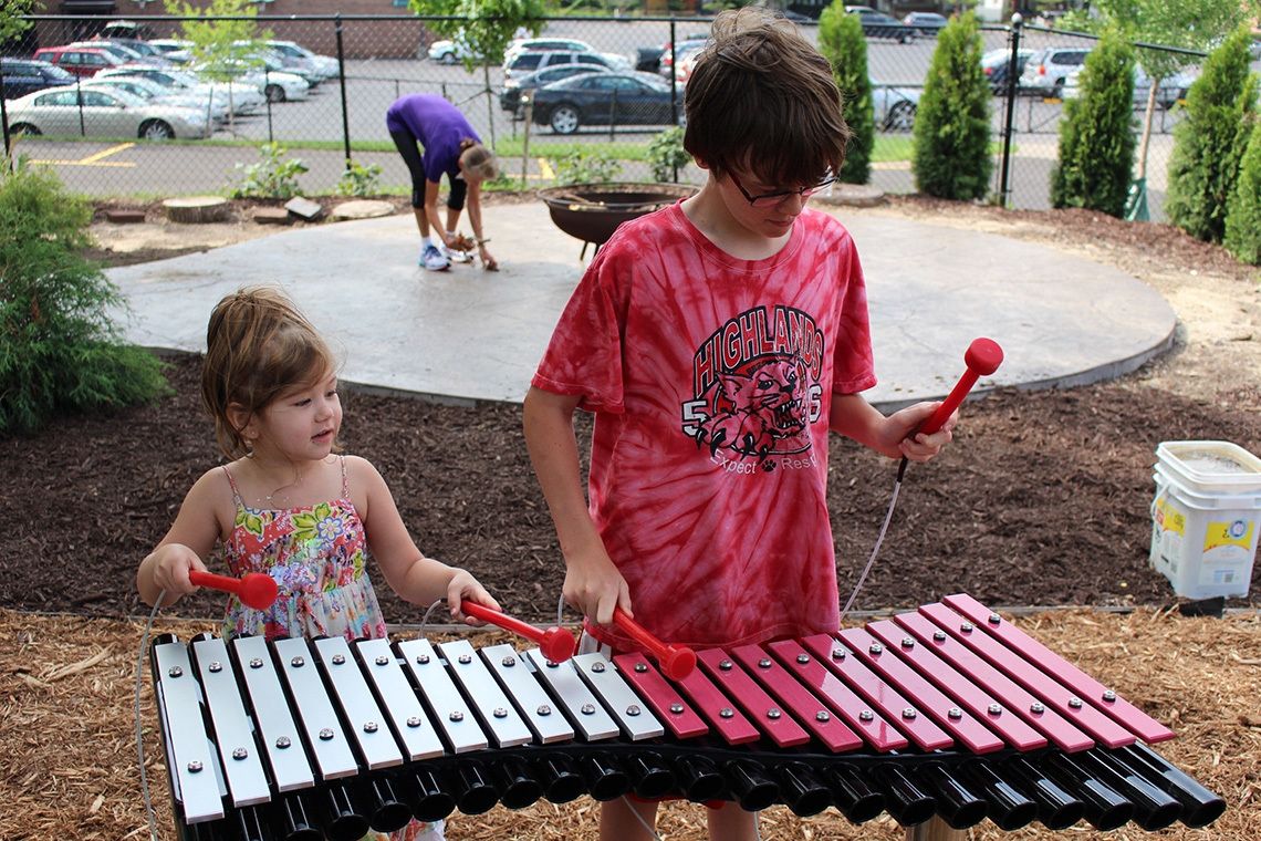 two children playing a large outdoor xylophone in playground
