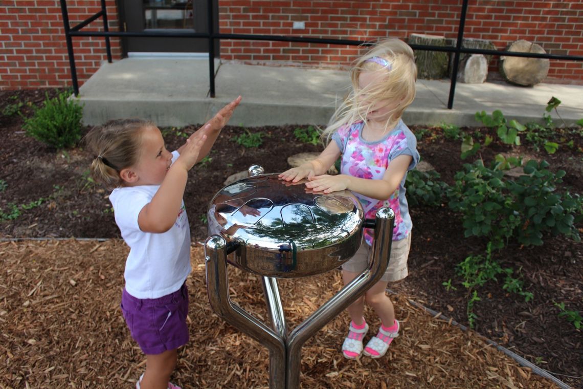 two little girls playing a Stainless Steel tongue drum in playground