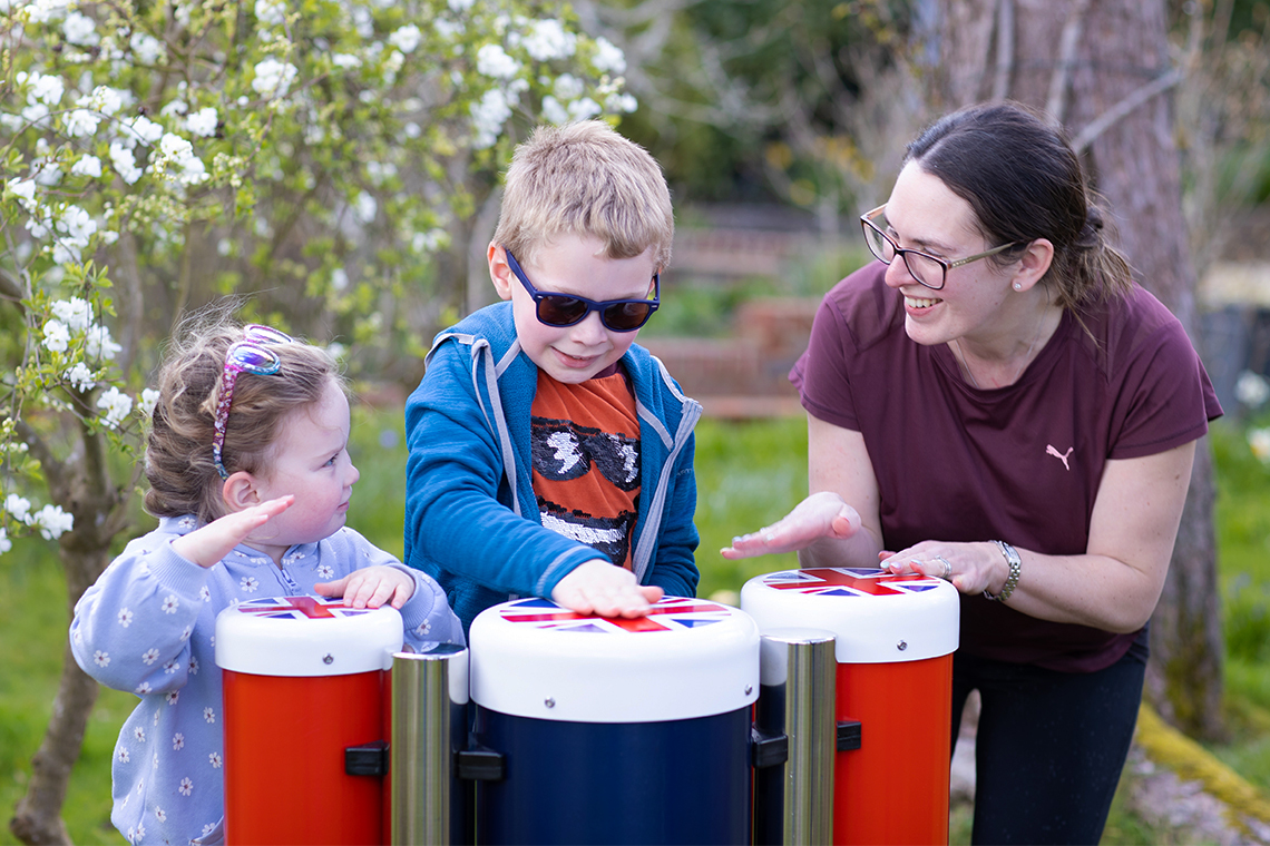 a family playing outdoor conga drums in red white and blue topped with the union flag