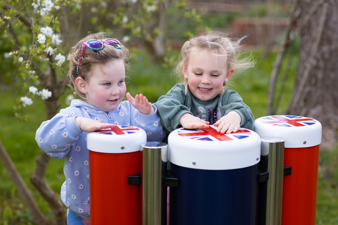 two young girls playing red white and blue outdoor conga drums