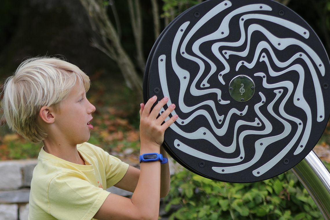 a close up image of a blond boy facing a large rain wheel 