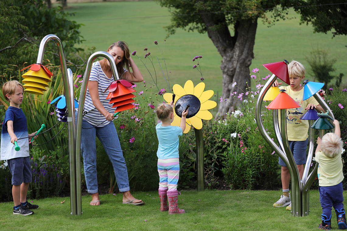 three outdoor musical instruments inspired by nature being played by a mother and four young children