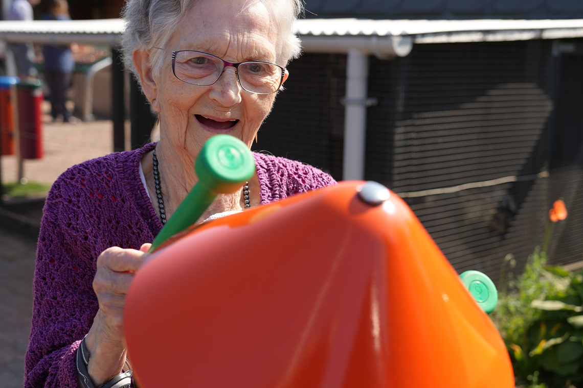 senior lady playing outdoor musical bells in a senior living home