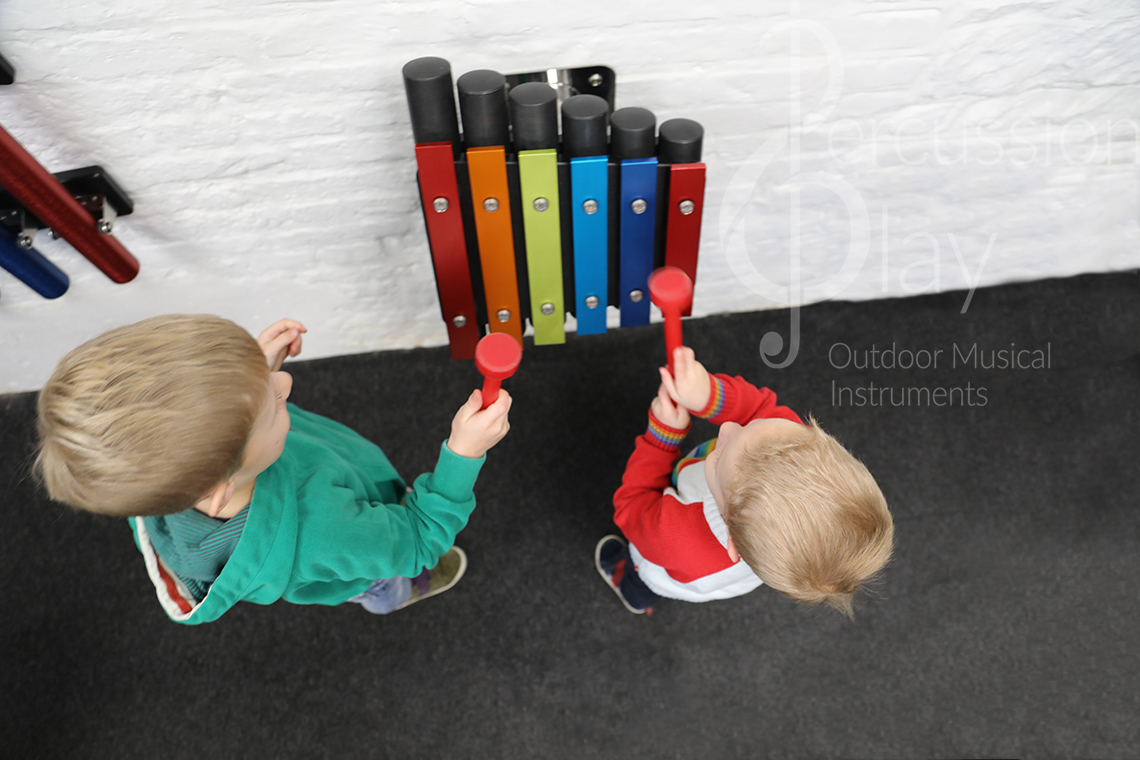 a small rainbow coloured outdoor metallophone for wall mounting suitable for nurseries and kindergartens
