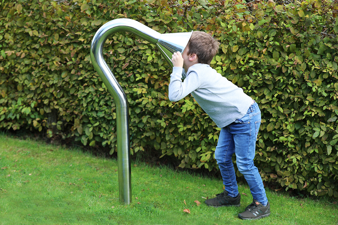 boy speaking into a large stainless steel cone playground talk tube