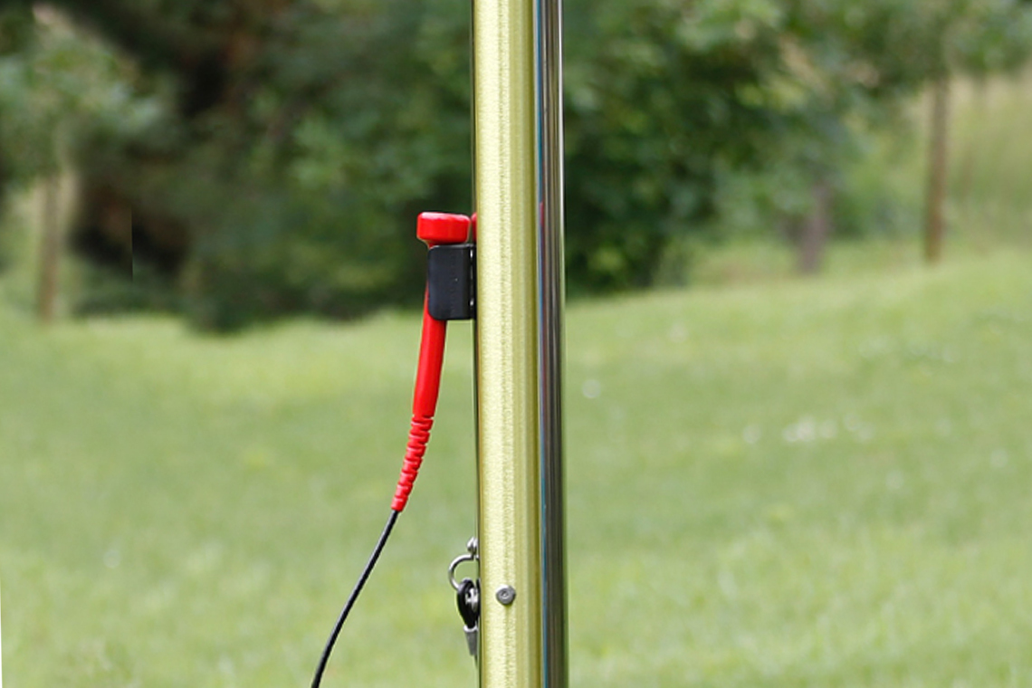 a yellow outdoor musical chime with mallet in a musical garden