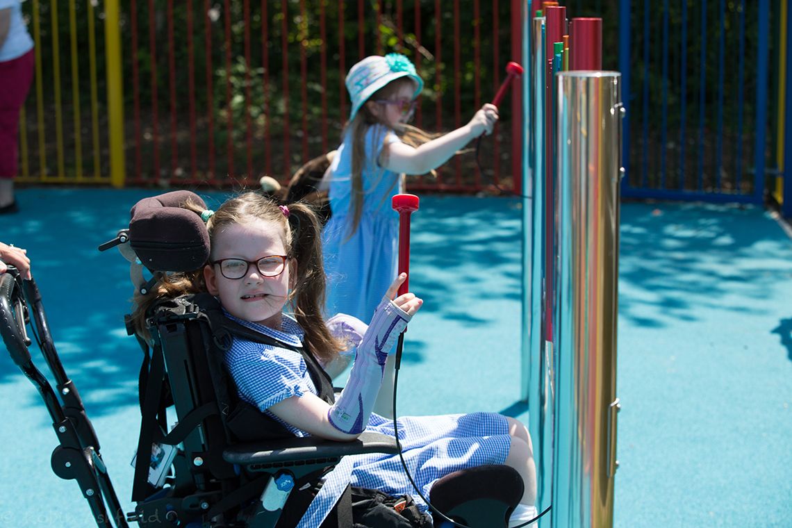 Young girl with special needs playing a chimes in school playground