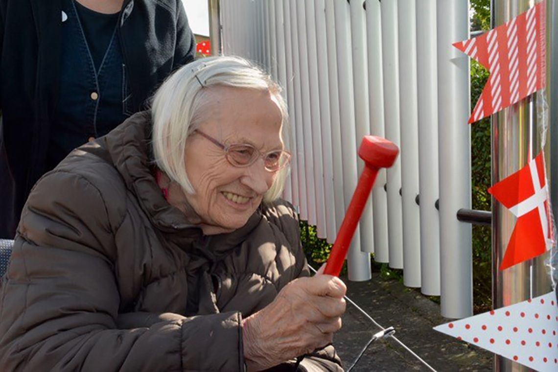 older lady in a wheelchair playing an outdoor musical instrument